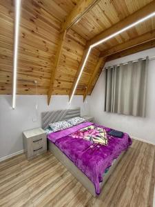 a bedroom with a bed with purple sheets and a wooden ceiling at bag evi in Mardakan