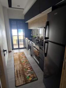 a kitchen with a refrigerator and a rug on the floor at Appartement Ennour de Martil in Martil