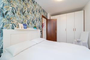 1 dormitorio con cama blanca y papel pintado tropical en GIOTTO Guesthouse, en Due Carrare 33 fotos más