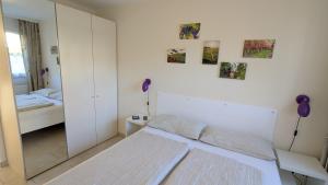 a white bedroom with a bed and a mirror at FeWo Apland in Landau in der Pfalz