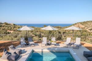 Una piscina con sillas y sombrillas junto al mar. en Allargo Project, en Gerani