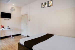 a bedroom with a bed and a desk and a tv at Collection O GNRC Hospital Dispur Formerly Shree Vinayak Guest House in Guwahati