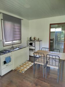 - une cuisine avec une table, des chaises et une cuisinière dans l'établissement 3R Lodge Bungalows, à Toanoano