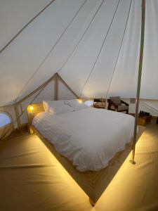 Al RakaSahara Dream Camp的帐篷里的卧室，有一张白色的床