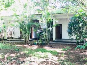 a white house with trees in front of it at Royal Galaxy Villa in Embilipitiya