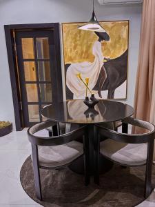 a black table with two chairs and a painting at Jeffreys Apartments in Lagos +2 photos
