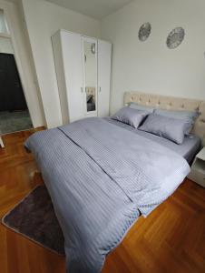 a large bed in a bedroom with wooden floors at Apartman Harmony in Lukavica