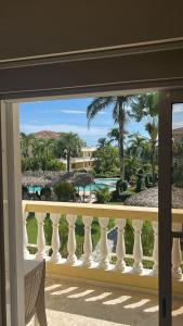 a balcony with a view of the ocean and palm trees at Marvilla - Coastal Condo Poolside & Ocean View in Boca Chica +2 photos