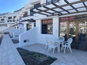 a patio with a table and chairs on a house at Casa Feliz en el complejo Las Fresas in Puerto Rico de Gran Canaria