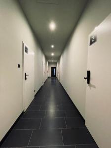 a long hallway with white doors and a tile floor at KWADRAT hostel 