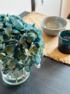 a glass vase filled with blue flowers on a table at L'Ecume - Le Rheu in Le Rheu