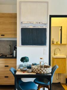 a kitchen with a table and two blue chairs at L'Ecume - Le Rheu in Le Rheu