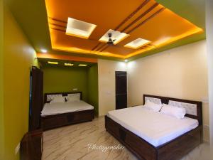 two beds in a room with green walls and a ceiling at ABS Palace Ayodhya in Faizābād