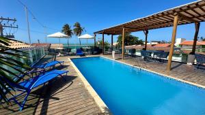 a swimming pool with blue chairs and umbrellas at Pousada SandBeach in Flecheiras