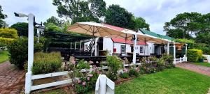 a restaurant with tables and umbrellas in a garden at Belvidere Garden Apartment in Knysna