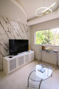 a living room with a large television and a glass table at Apartamento Confortável e Acolhedor in Diamantina