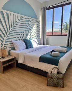 a bedroom with a large bed with a large window at Kue Hotel Maafushi in Maafushi