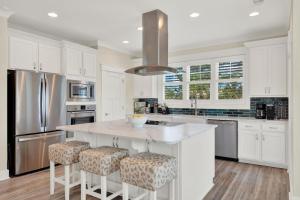 a kitchen with white cabinets and a large island with bar stools at Blue Heaven Villa in Tybee Island