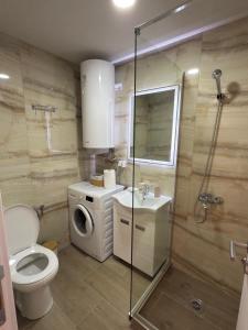 a bathroom with a toilet a sink and a washing machine at Relax Apartmani Niš in Niš