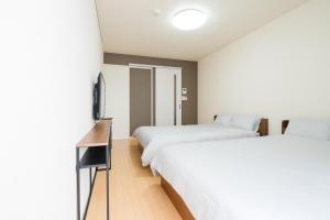 a hotel room with two beds and a television at Heights Nagomi in Otsu