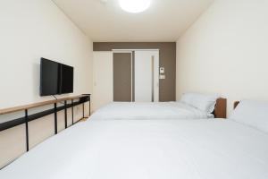 two beds in a room with a flat screen tv at ハイツNagomi in Otsu