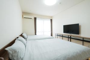 a bedroom with two beds and a flat screen tv at ハイツNagomi in Otsu
