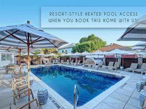 a swimming pool with chairs and umbrellas at Silver Seas 103 in Tybee Island
