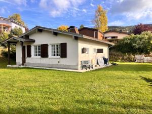 a small white house with a green yard at Chalet authentique au cœur du Mont d'Or in Métabief