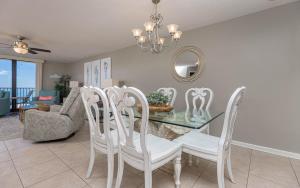 een eetkamer met een glazen tafel en witte stoelen bij Phoenix VI 6708 condo in Orange Beach