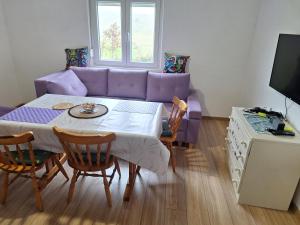 a living room with a table and a purple couch at Horizont Cemerno 