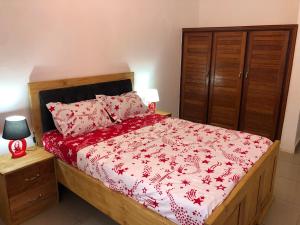 a bedroom with a bed with a red comforter at Grand Appartement à essos mobile in Yaoundé
