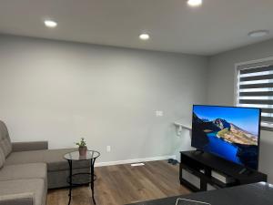 a living room with a couch and a flat screen tv at Kris Comfort Garden Suite in Edmonton
