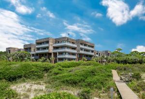 a building on top of a grassy hill with a wooden bridge at 2371 Shipwatch Villa by Akers Ellis Rentals in Kiawah Island