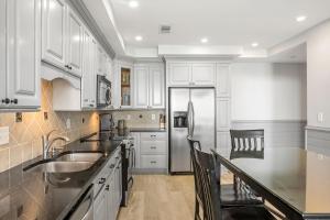 a kitchen with white cabinets and a stainless steel refrigerator at 2371 Shipwatch Villa by Akers Ellis Rentals in Kiawah Island