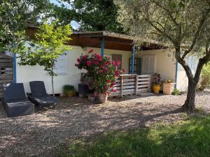 a house with two chairs and a fence and flowers at Chalet Proche mer in Latour-Bas-Elne
