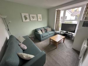 a living room with a green couch and a television at Hiraeth Môn in Menai Bridge