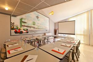 a conference room with tables and a white screen at Cit'Hotel Du Circuit in Magny-Cours