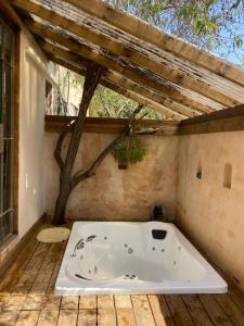 a bath tub sitting on a deck with a roof at צימר השקדיה in ‘En Hod