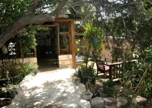 a wooden door with a bench in a garden at צימר השקדיה in ‘En Hod +1 photo