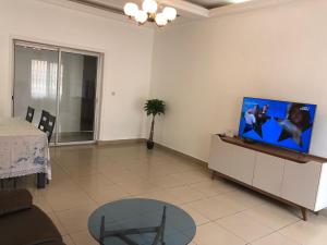 a living room with a flat screen tv on a cabinet at Grand Appartement à essos mobile in Yaoundé
