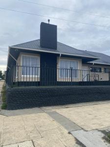 a house with a black fence in front of it at Hostal Like Home in Puerto Natales