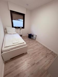 a white bedroom with a bed and a window at Villa Heusenstamm in Heusenstamm +1 photo