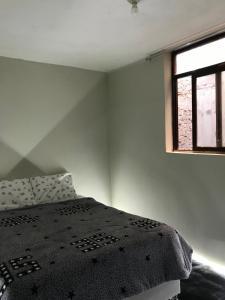 ein Schlafzimmer mit einem Bett mit einer schwarzen Decke und einem Fenster in der Unterkunft Habitación en el corazón de Chiclayo in Chiclayo + 1 Foto