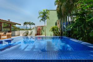 a swimming pool with a blue tile floor and trees at Casa Varanda Guaecá Pet Friendly, Heated Pool in São Sebastião
