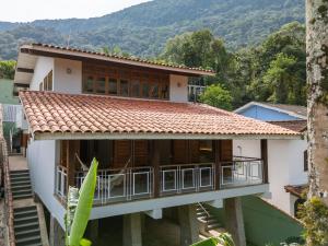 a house with a balcony and mountains in the background at Casa Varanda Guaecá Pet Friendly, Heated Pool in São Sebastião +64 photos