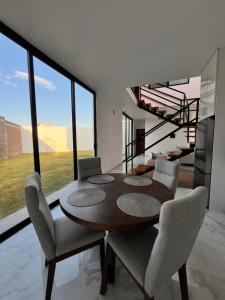 a dining room with a table and chairs and a staircase at Puerta Sevilla in Saltillo