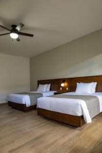 a bedroom with two beds and a ceiling fan at Aura Hotel in Uruapan del Progreso