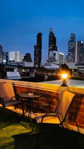een tafel en stoelen op een balkon met een skyline van de stad bij Aura Hostel in Bangkok