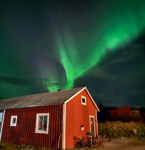 a red barn with the aurora in the sky at Folkja gård i Höga kusten in Noraström