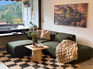 ein Wohnzimmer mit einer grünen Couch und einem Tisch in der Unterkunft Bergherz Berchtesgaden in Berchtesgaden